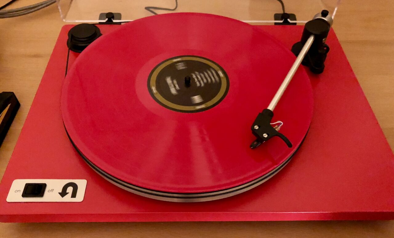 Red manual turntable playing a red record
